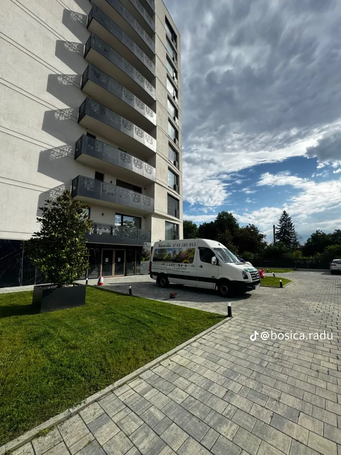 Duba albă Radu Garden parcată lângă spațiul verde al unui bloc din Timișoara.