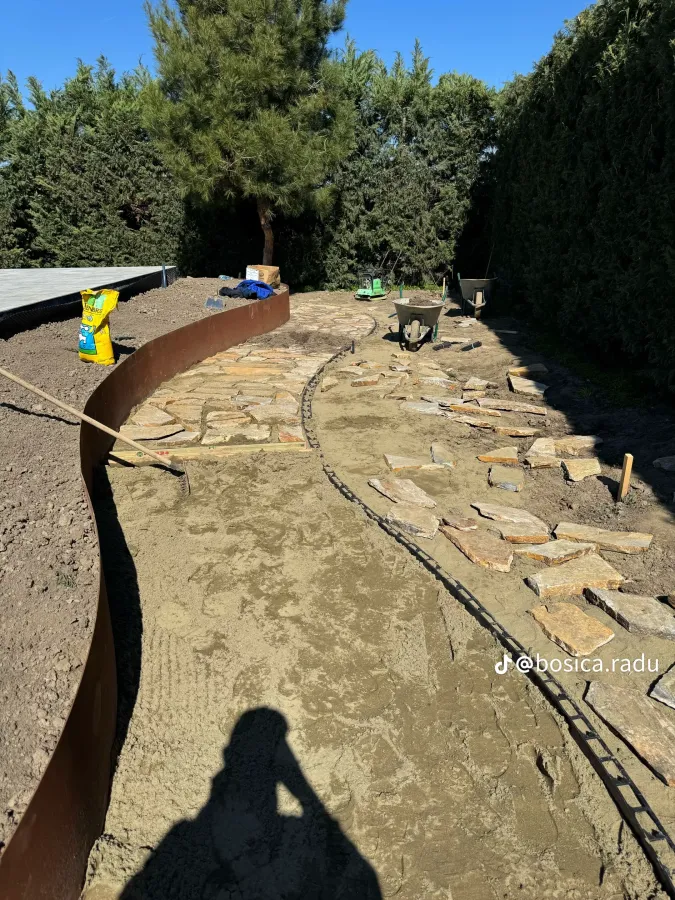Alee din lespezi de piatră montată bucată cu bucată, mărginită de bordură din corten.